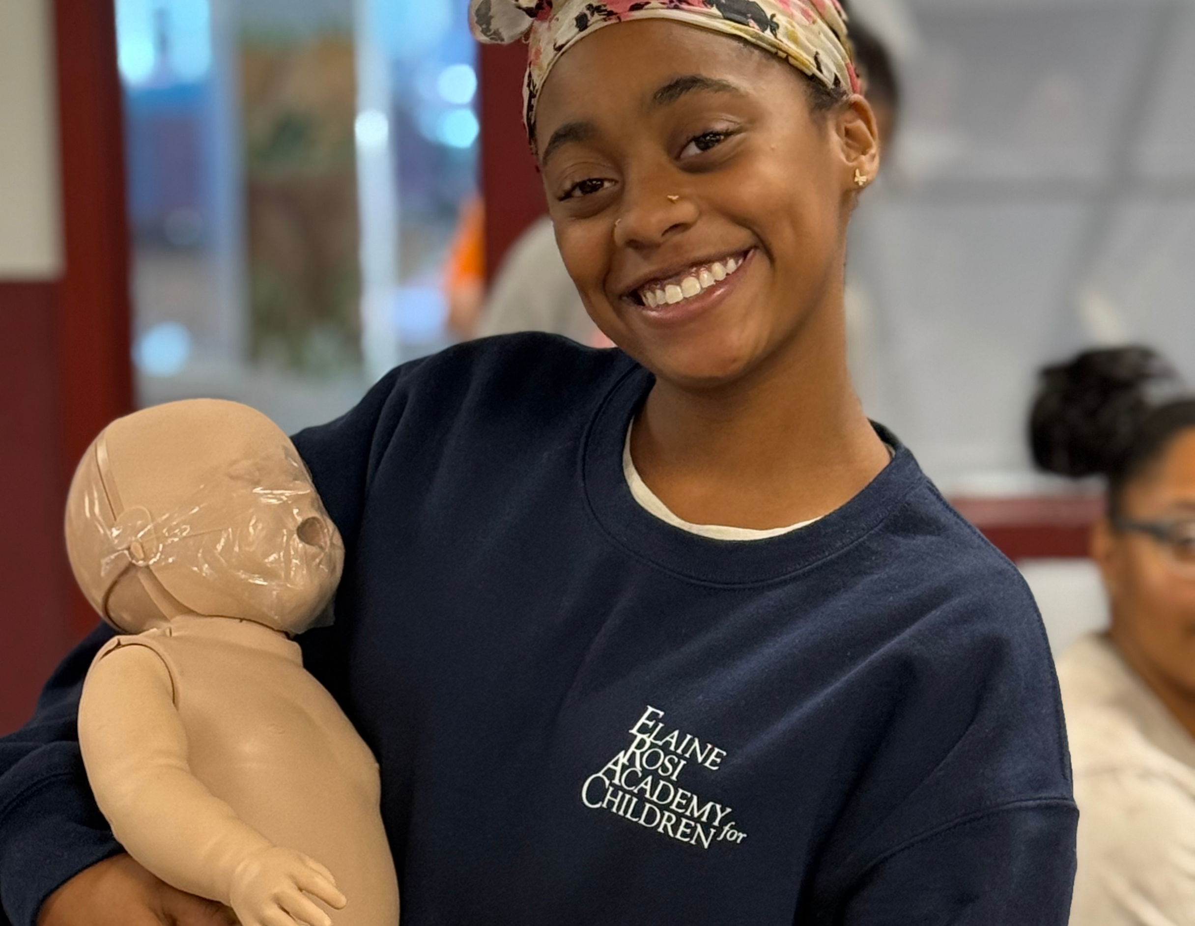 Teacher holding an infant mannequin for CPR training