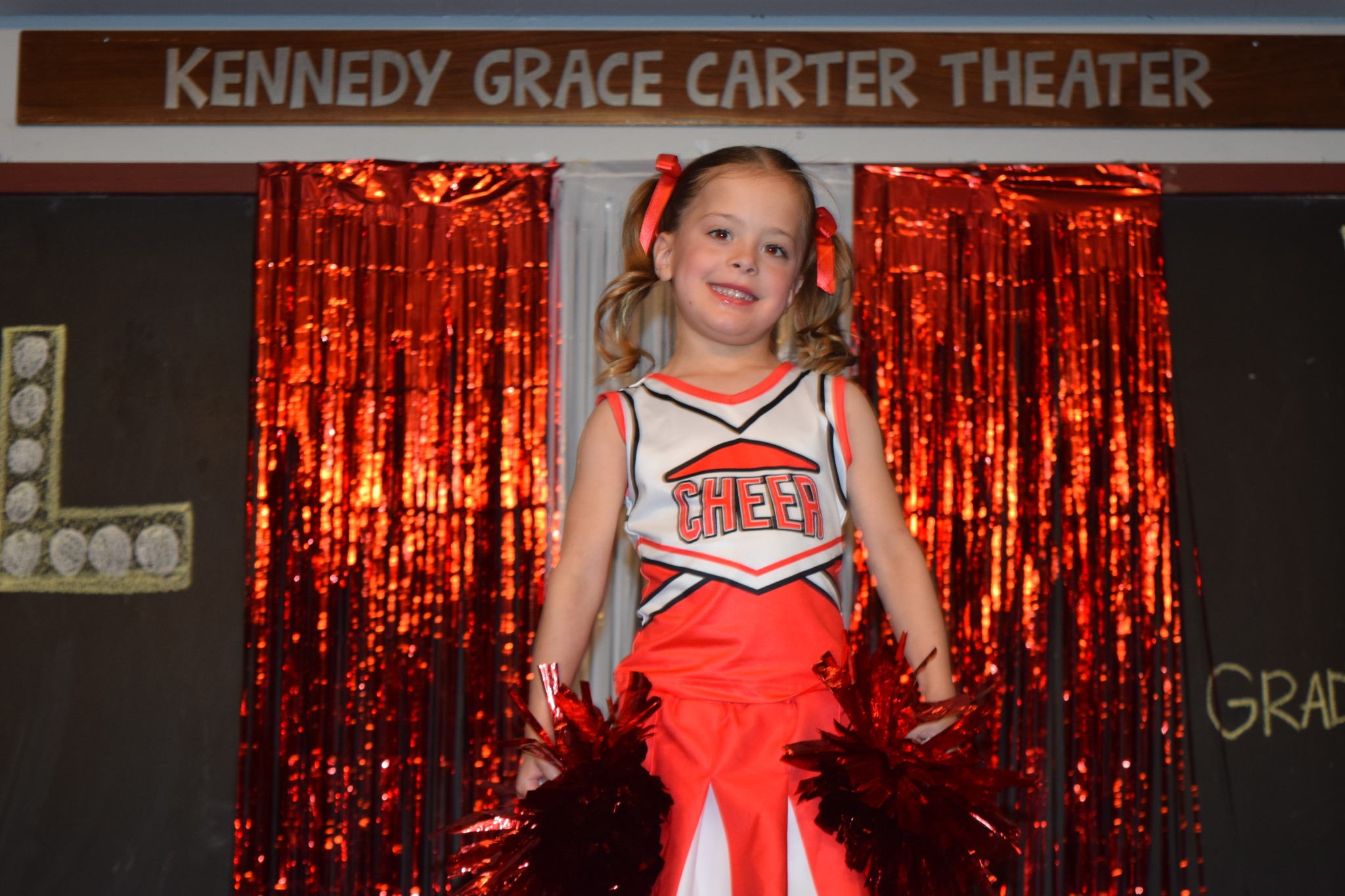 Child in cheerleading costume performing on stage.